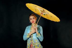 Aziatisch vrouw in trekkracht kebaya draag- paraplu Aan zwart achtergrond foto