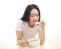 mooi jong zuiden oosten- Aziatisch vrouw Holding Chinese leeg eetstokje soep lepel kom werktuig doen alsof acteren poseren zien eten smaak voeden aanbod tevredenheid lekker wit achtergrond gelukkig foto