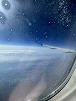 visie van de vliegtuig venster. mooi cloudscape met blauw lucht. geweldig panorama bovenstaand wit wolken net zo gezien door venster van een vlak. op reis door lucht concept. selectief focus. foto