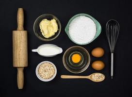 hulpmiddelen en ingrediënten voor het deeg op zwarte achtergrond foto