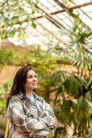 een vrouw bewondert planten in een serre. foto