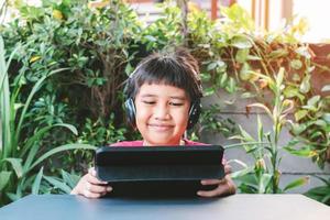 Aziatische schattige jongen spelen op de tablet foto