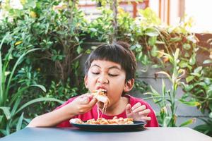 Aziatische leuke jongen die gelukkig pizza zit te eten foto