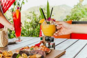 Dames vieren roosteren drinken buiten met cocktails. foto