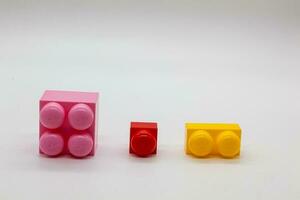 kinderen speelgoed- bouwer Lego verschillend maten. rood, roze en geel en groen blokken. foto in hoog kwaliteit. geïsoleerd.