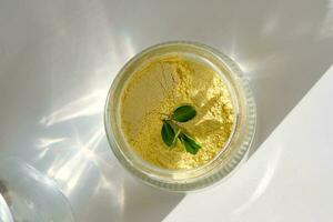 een Open pot van een geel kurkuma gelaats schrobben tonen uit haar textuur. foto