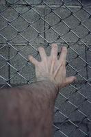 hand die een metalen hek bereikt foto