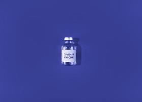 flesje met covid 19-vaccin op blauwe achtergrond medische eenvoudige plat leggen foto