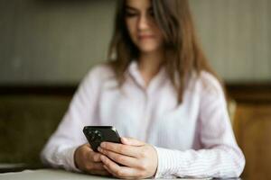 jong mooi brunette vrouw Holding smartphone, typen bericht, sms'en, chatten, browsen mobiel appjes, internetten, controle sociaal netwerken, e-mail. foto