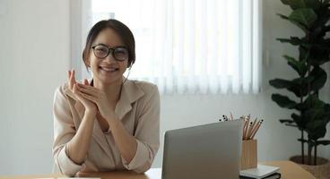 portret van glimlachende zakenvrouw zittend aan een bureau in het kantoor dat op laptop werkt foto