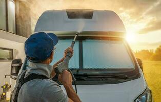 mannen druk het wassen zijn camper busje rv gedurende toneel- zonsondergang foto