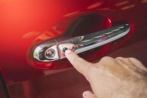 menselijke hand keyless entry-knop op de autodeurhendel van de rode auto in te drukken foto