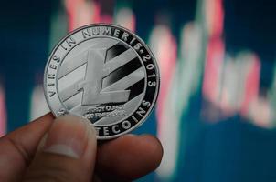 man met cryptocurrency litecoin-munt met een virtuele beursgrafiekachtergrond foto