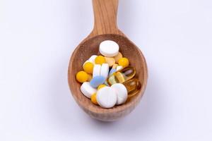 geneeskunde pillen en drugs in houten lepel op witte achtergrond met kopie ruimte foto