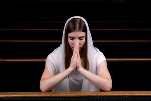 een christelijk meisje dat met nederig hart bidt in de kerk foto