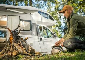 mannen hangende uit in de buurt kampvuur en camping in zijn camper busje foto