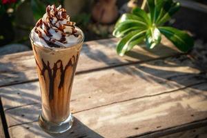 koffie frappe met slagroom op oude houten tafel in de ochtendzon foto