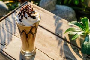 koffie frappe met slagroom op oude houten tafel in de ochtendzon foto