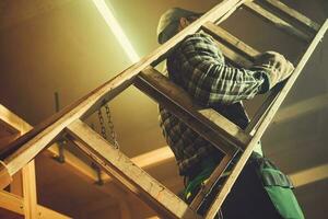 arbeider in beweging houten ladder binnen zijn schuur foto