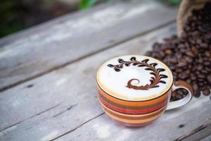 hete cappuccino koffie op oude houten tafel met gebrande koffiebonen foto