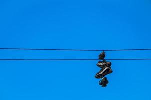 sneakers die aan draden tegen een blauwe hemel hangen foto
