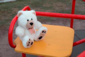 close-up van een teddybeer zittend op een schommel voor kinderen foto