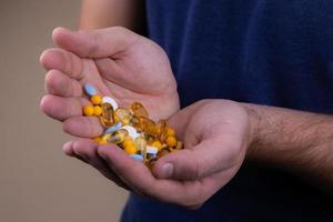 een stapel multi gekleurde pillen in mannelijke handen foto