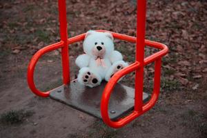 close-up van een teddybeer zittend op een schommel voor kinderen foto