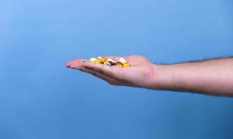 een stapel multi gekleurde pillen in mannelijke handen foto