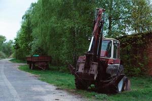 rode oude roestige tractor in een veld in de buurt van de weg foto