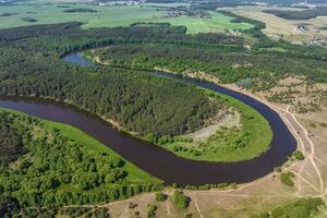 panoramisch visie van een hoog hoogte van een meanderend rivier- in de Woud in de buurt dorp foto