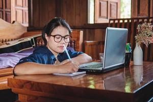 jonge vrouw werken zittend op de bank met laptop thuis foto