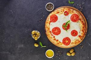 Italiaanse pizza en ingrediënten voor het koken op een zwarte betonnen achtergrond