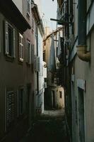 romantisch versmallen steeg van oud historisch kust- stad- piran in Slovenië bekleed door huizen met Gesloten venster luiken en hangende drogen kleren foto