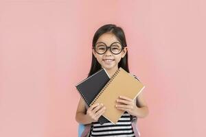 schoolmeisje knuffelen boek vervelend rugzak glimlachen geïsoleerd Aan roze achtergrond foto
