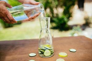 water in de fles met komkommer gieten foto