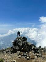 Aziatisch Mens staand Aan top van een dichtbij berg op zoek Bij monteren sindoro. west Java, Indonesië, maart 16, 2023 foto