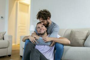 liefhebbend dezelfde seks mannetje homo paar aan het liegen Aan sofa Bij huis en ontspannend, knuffelen samen foto