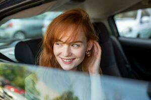 mooi jong zakenvrouw zittend Aan terug stoel van een auto en op zoek buiten de venster. vrouw bedrijf uitvoerend op reis door een taxi. foto