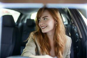 mooi jong vrouw het rijden haar nieuw auto Bij zonsondergang. vrouw in auto. dichtbij omhoog portret van aangenaam op zoek vrouw met blij positief uitdrukking, vrouw in gewoontjes slijtage het rijden een auto foto