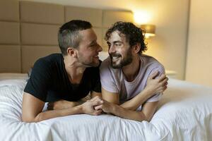 gelukkig homo paar aan het liegen naar beneden Aan de bed Bij huis, knuffelen en flirten. lgbt homo paar liefde momenten geluk concept foto