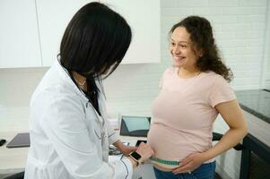 dokter verloskundige gynaecoloog maatregelen de hoogte van fundus van de baarmoeder van een zwanger vrouw gedurende medisch controle foto