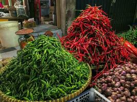 stapel van vers rood pepers groen pepers en ui in de traditioneel markt voor Koken ingrediënten. foto