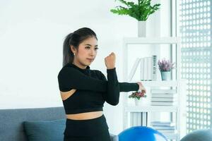 Aziatisch jong gezond vrouw in sportartikelen beoefenen yoga Bij huis, sport meisje oefening in leven kamer Bij huis foto