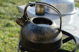 waterkoker met water Aan de fornuis buiten. koken water in moeilijk keer. foto