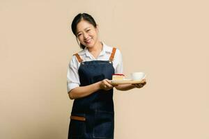 portret van Aziatisch meisje serveerster barista vervelend schort Aan licht bruin achtergrond foto