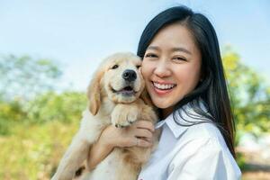 jong Aziatisch vrouw Holding gouden retriever puppy in buitenshuis. eigenaren kijken Leuk vinden hun honden. liefde huisdieren concept. foto