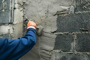 close-up hand van werknemer die cement aan de muur pleistert voor het bouwen van een huis foto