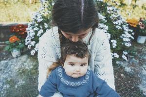 jonge moeder haar baby knuffelen en genieten van een lentedag in de tuin foto