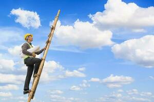 Aziatisch bedrijf Mens ingenieur beklimming omhoog ladder met blauw lucht, carrière groei en succes concept foto